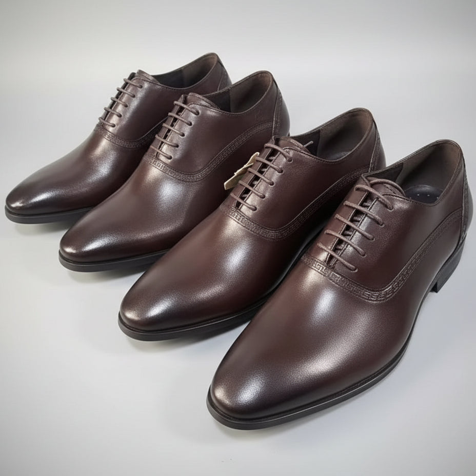 Three brown leather dress shoes on a speckled surface