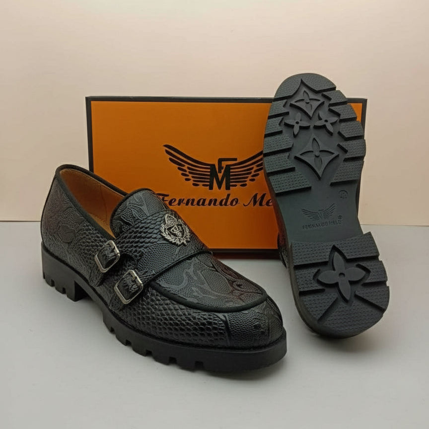 Black shoe with detailed design on a white surface, featuring a brand box in the background.