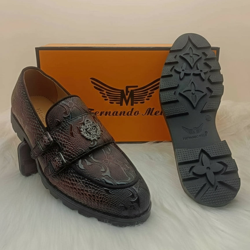 Brown leather shoe with decorative emblem on a white background, featuring 'Fernando Meli' branding.