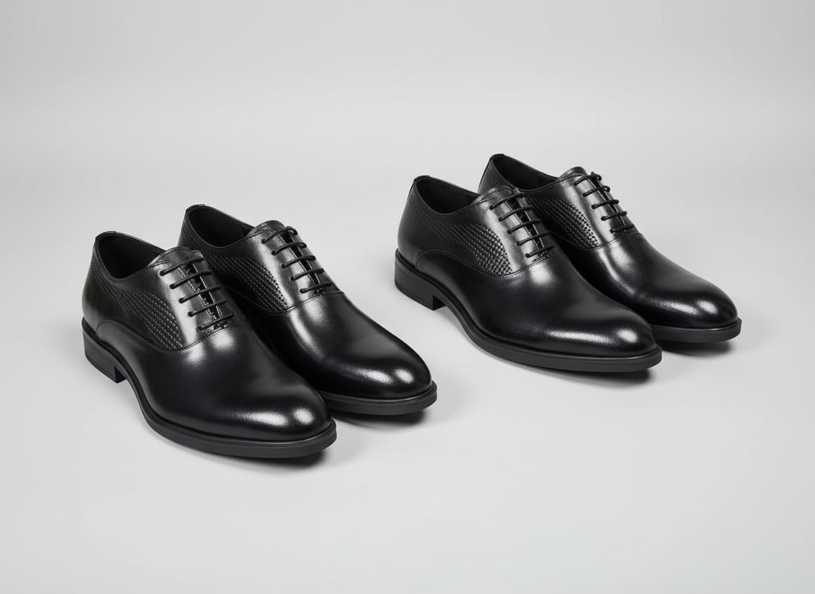 Four black dress shoes on a textured surface