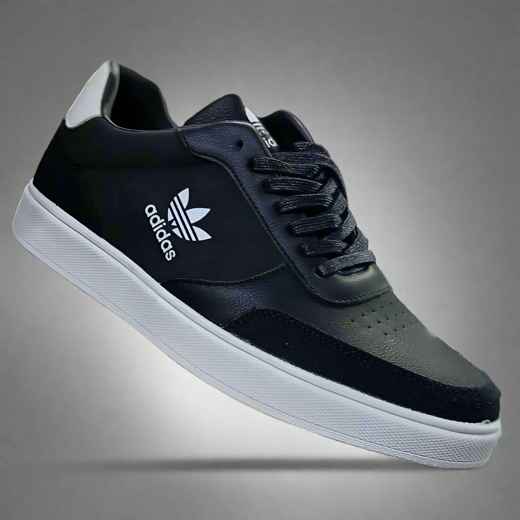 Black Adidas sneaker held in a hand with a blurred shoe store background