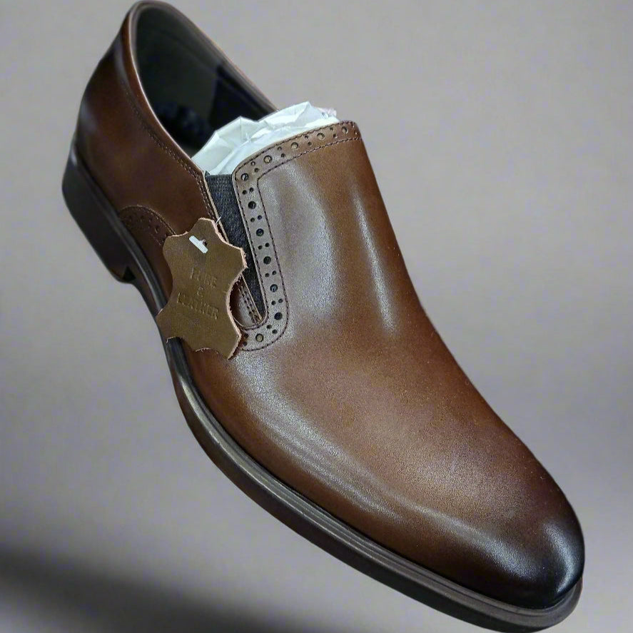 Brown leather shoe held by a hand with a blurred background