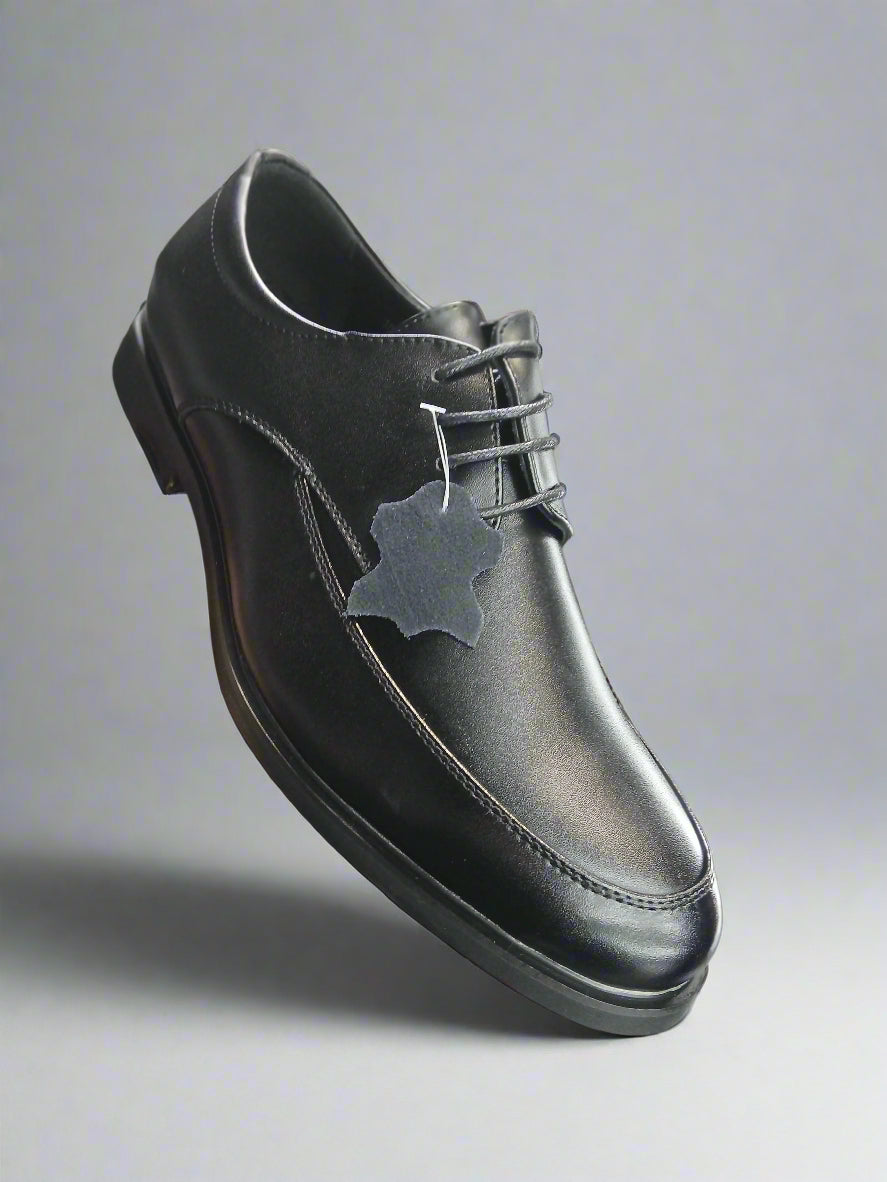 Black leather shoe held by a hand with a blurred store background