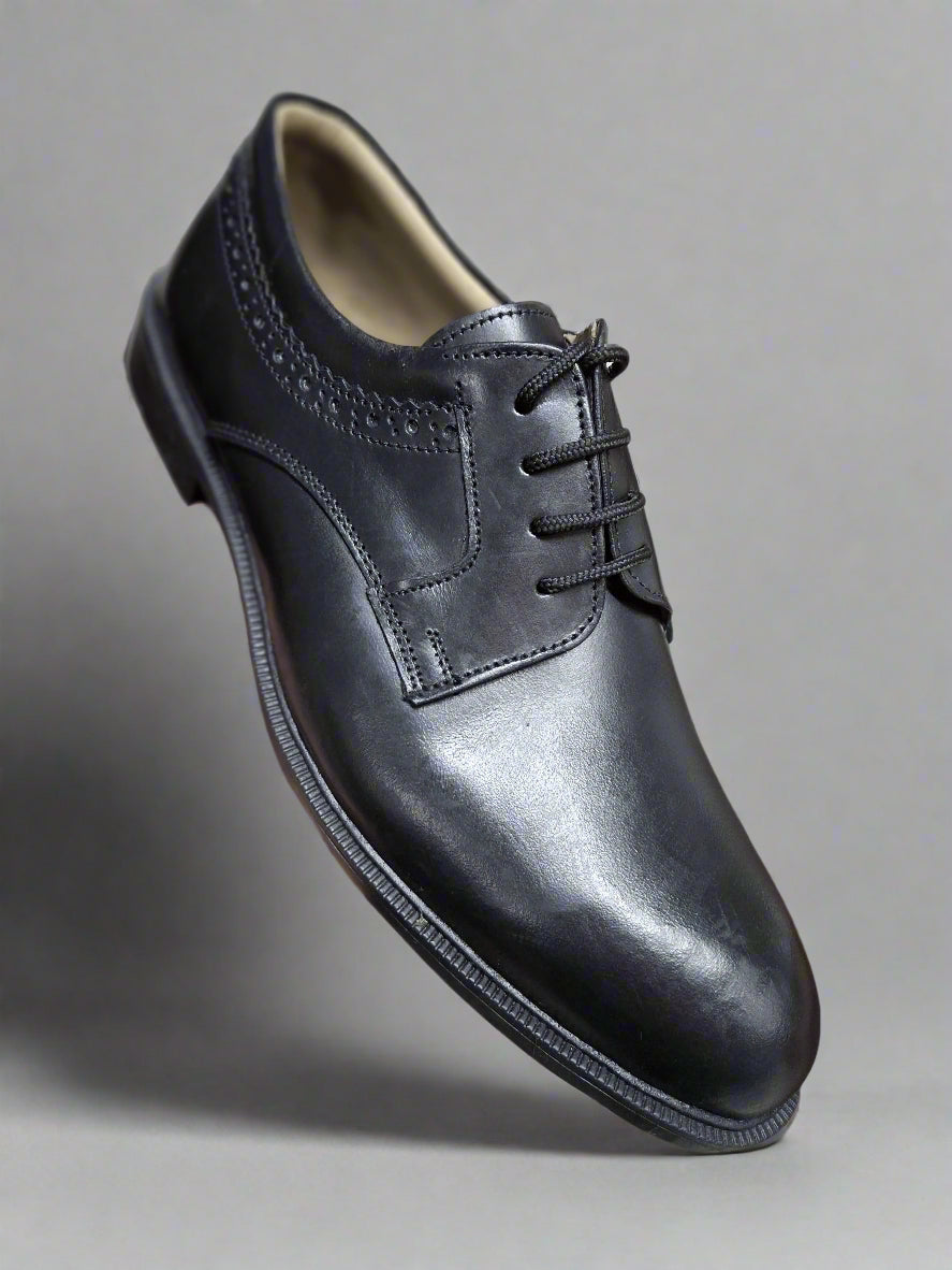 Black leather dress shoe held by a hand with a blurred background