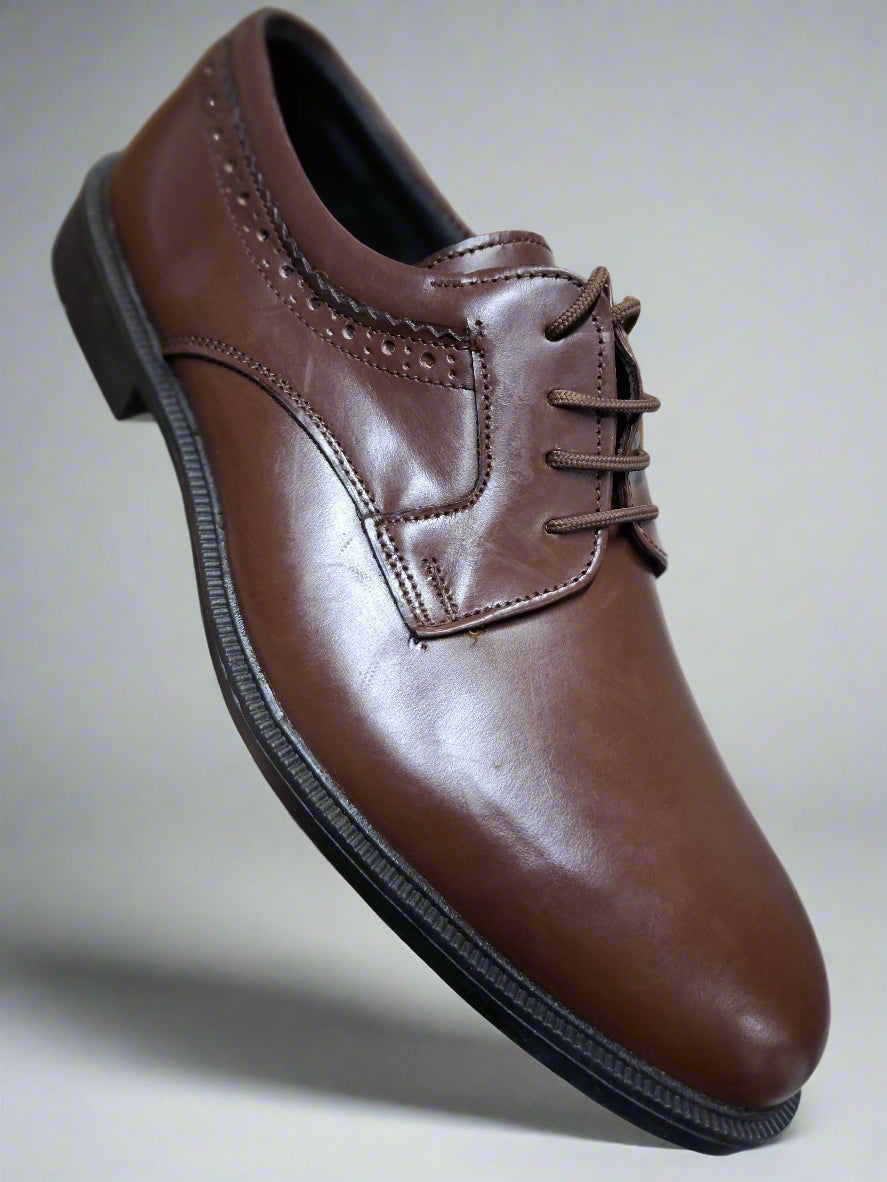 Brown leather dress shoe held by a hand on a tiled floor.