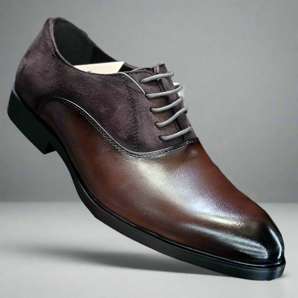 Brown leather shoe held by a hand against a blurred indoor background