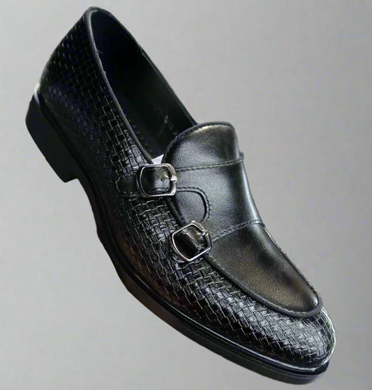 Black leather loafer with a textured pattern held by a hand against a blurred background