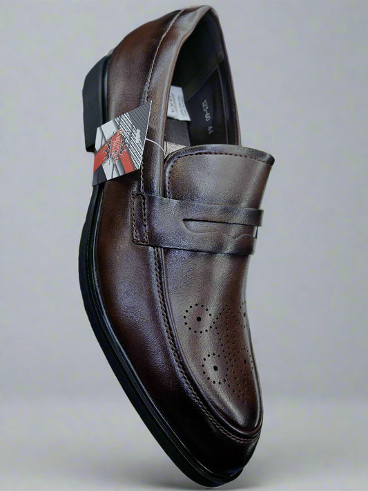 Brown leather shoe held by a person with a blurred background