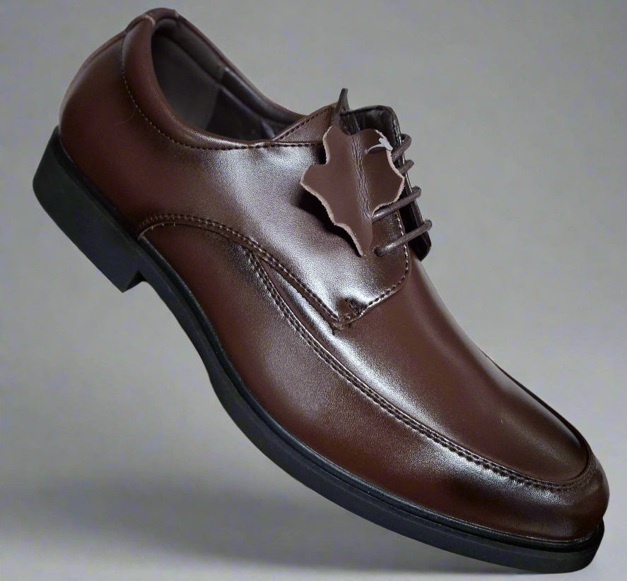 Brown leather shoe held by a hand against a neutral background