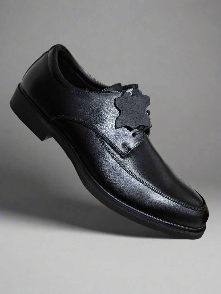 Black leather shoe with a decorative buckle held by a hand against a neutral background