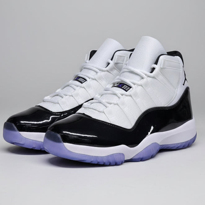 Pair of black and white sneakers with purple accents on a reflective surface.