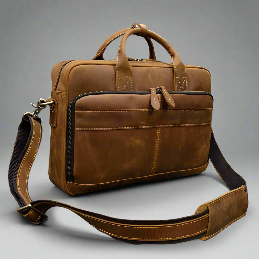Brown leather briefcase with shoulder strap on a textured surface