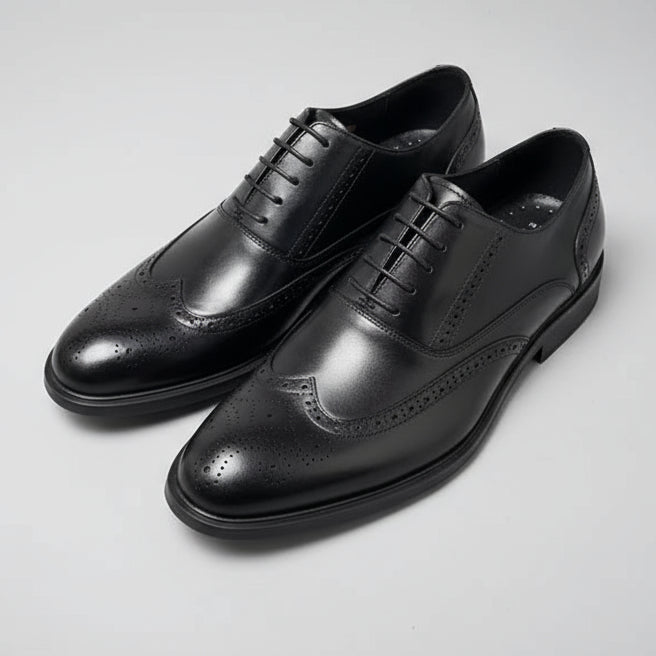 Four black dress shoes on a textured surface