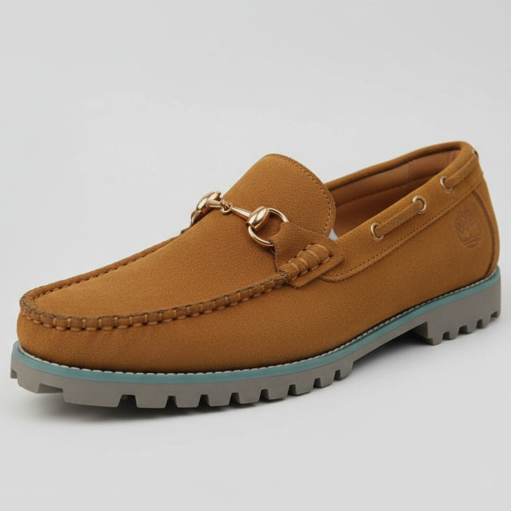 Tan loafer shoe held by a person with a blurred background