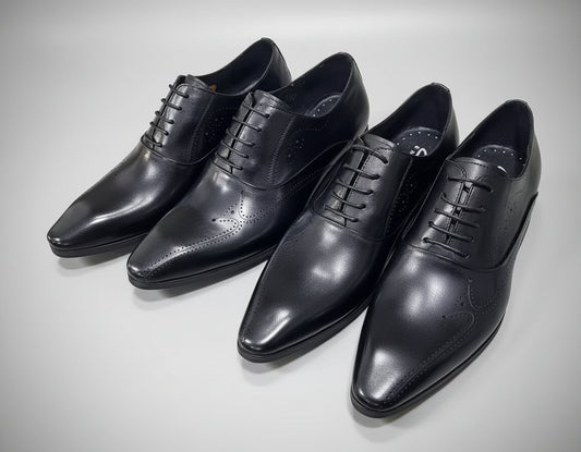 Four black dress shoes on a textured surface