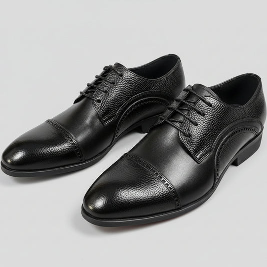 Pair of black leather dress shoes on a textured surface with a tag in the background.