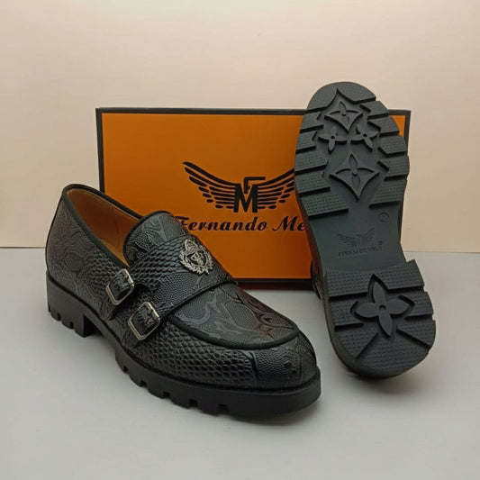 Black shoe with detailed design on a white surface, featuring a brand box in the background.