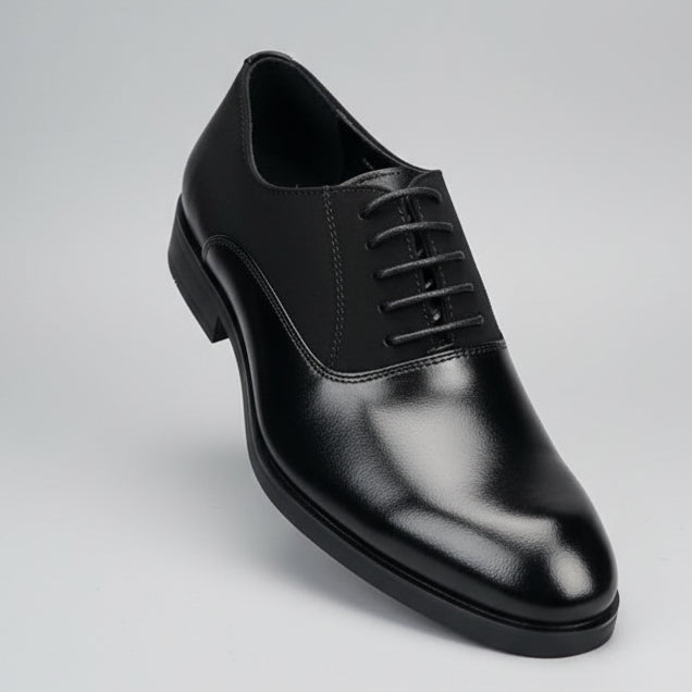 Black leather shoe held in a hand with shelves of shoes in the background