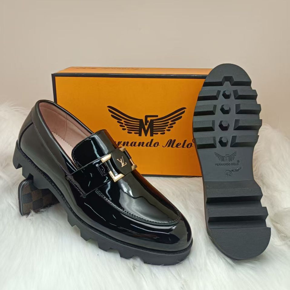 Black patent leather loafer with gold buckle and 'Fernando Melo' box on a light background