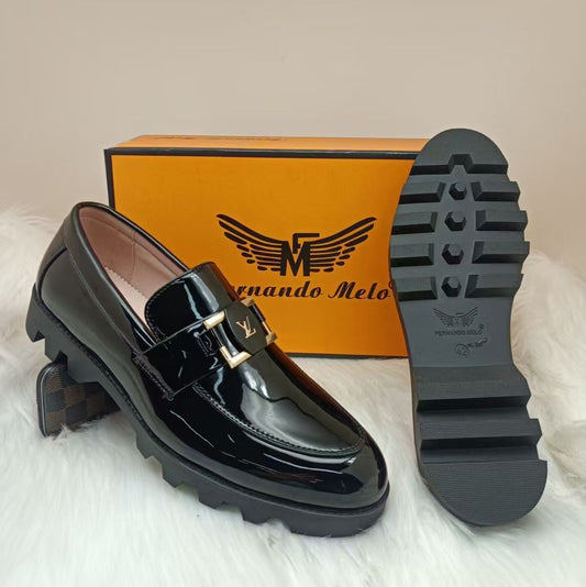 Black patent leather loafer with gold buckle and 'Fernando Melo' box on a light background