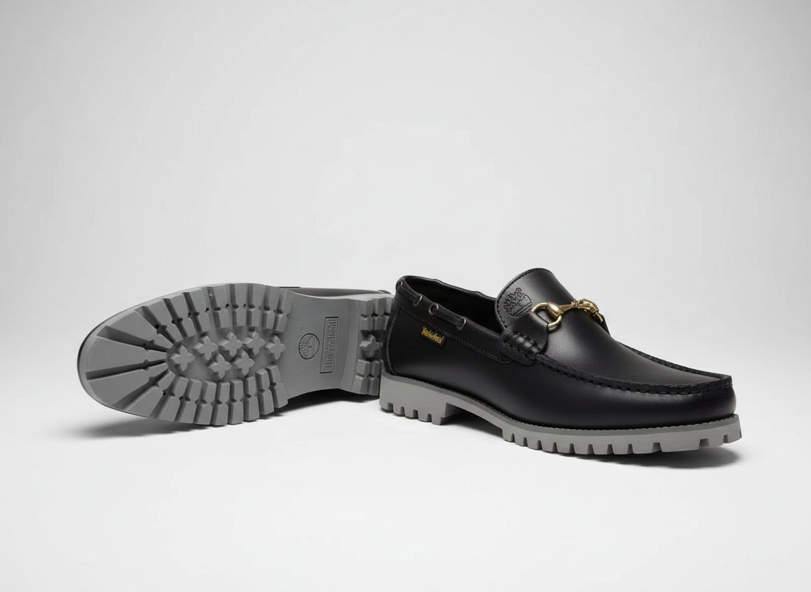 Black leather loafer with white sole on a wooden table