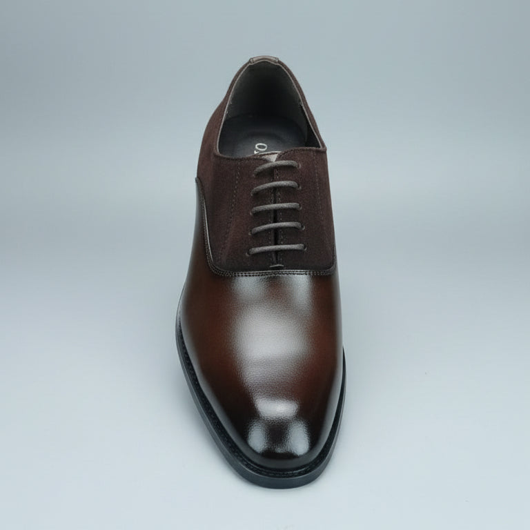 Brown leather shoe held by a hand with a shoe rack in the background