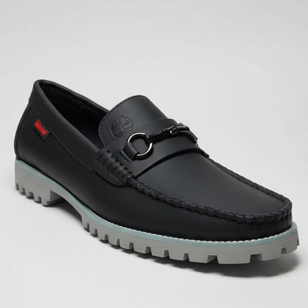 Black leather shoe held by a hand with a blurred background