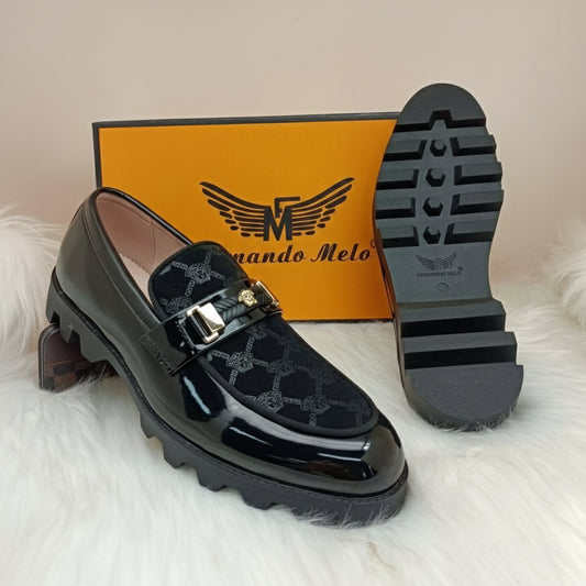 Black shiny loafer shoe with a branded box on a light gray background