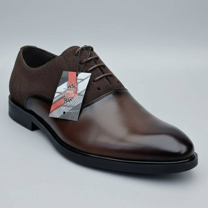 Brown suede shoe held by a hand with a blurred background