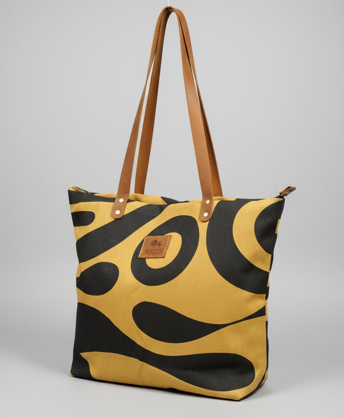 Person holding a yellow and black patterned bag in an indoor setting