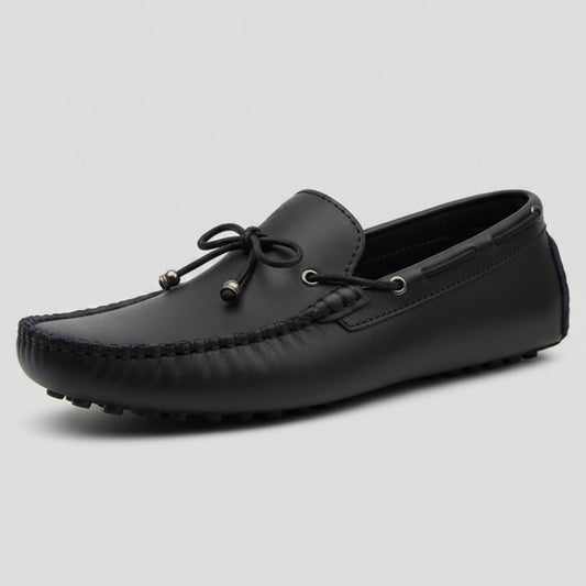 Black loafer shoe held by a hand with a blurred background