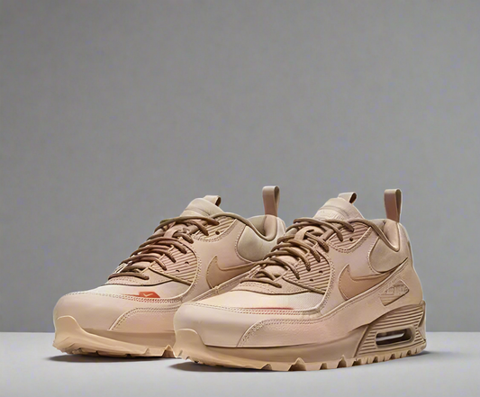 Pair of beige sneakers with a prominent brand logo on a white background