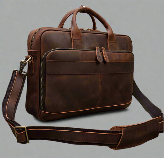 Brown leather briefcase with shoulder strap on a gray surface