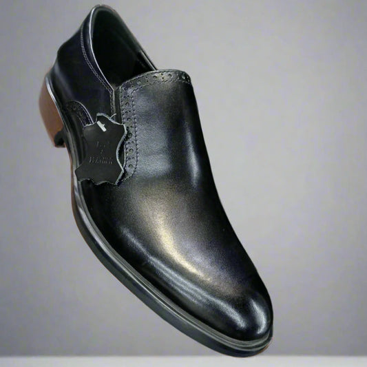 Black leather shoe held by a hand with a blurred background