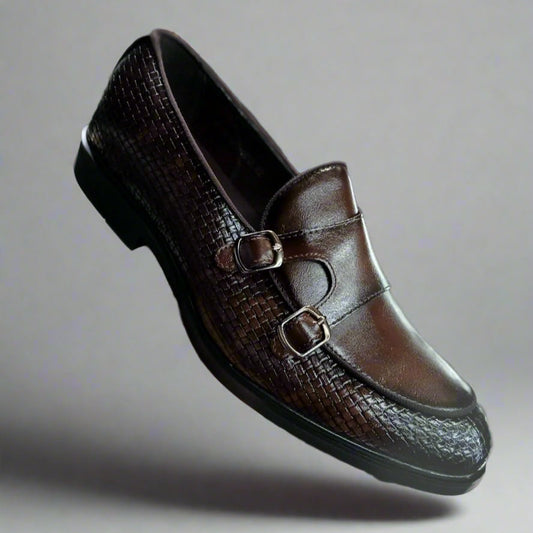 Brown leather loafer held by a hand with a blurred background