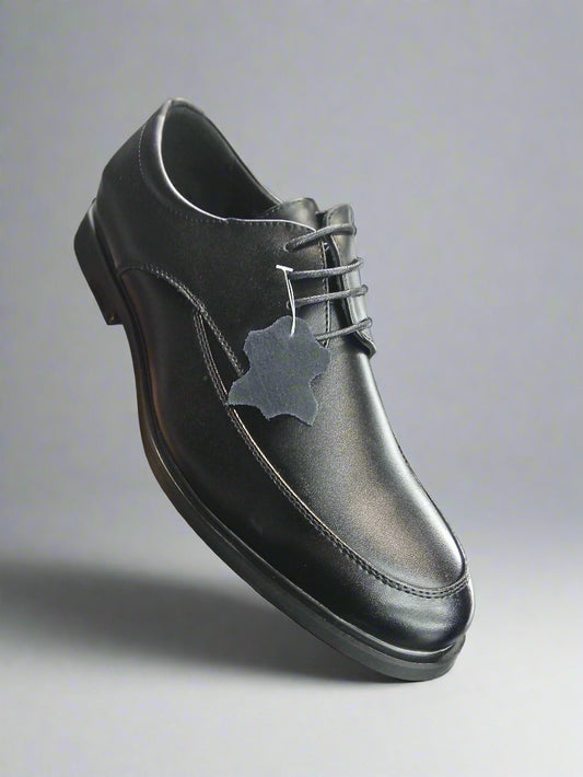 Black leather shoe held by a hand with a blurred store background