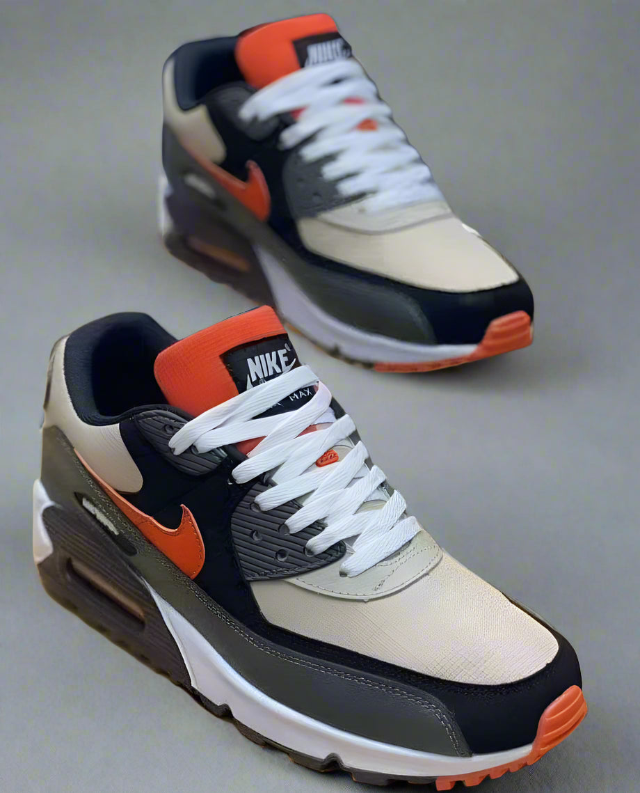Pair of Nike sneakers with orange and black accents on a wooden surface.