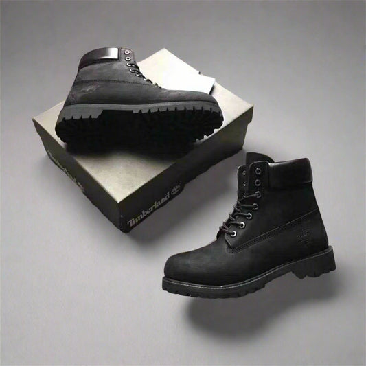 Black Timberland boots on a textured gray surface with a box in the background.