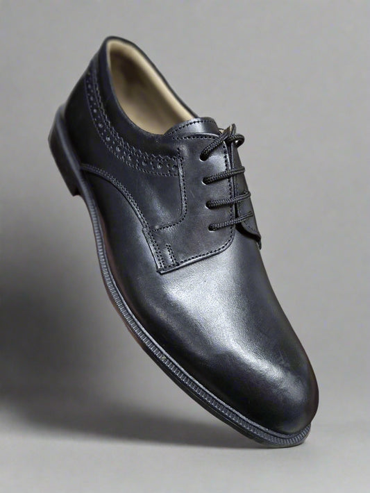 Black leather dress shoe held by a hand with a blurred background