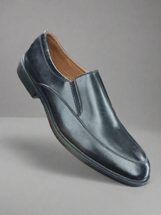 Black leather loafer shoe held in a hand with a blurred background
