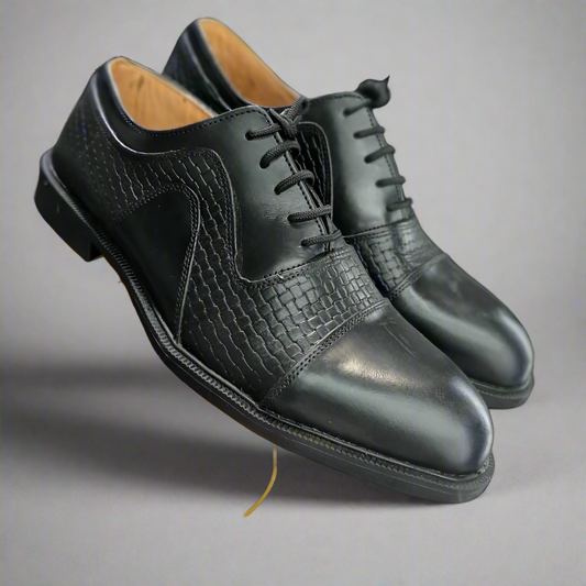 Black leather dress shoes with a textured toe cap on a white background