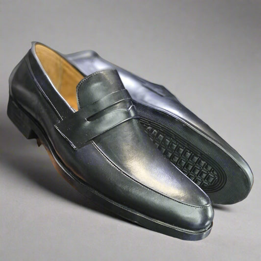 Black leather loafer held by a person with a blurred background