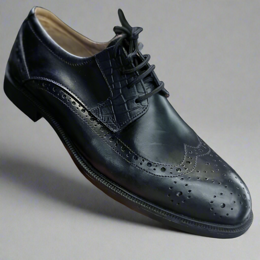 Black leather dress shoe held by a hand on a white background