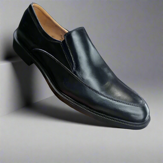 Black leather loafer shoe held by a hand on a white background