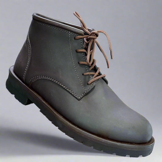Brown leather boot held by a hand with a blurred shoe store background