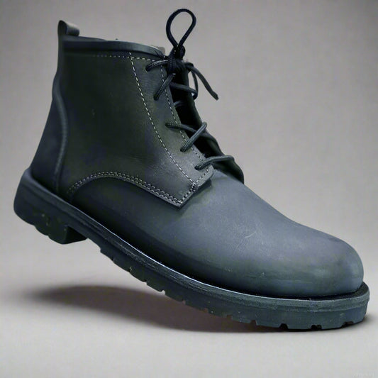 Black leather boot held by a hand with a blurred background