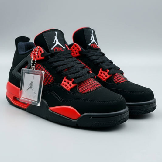 Black and red sneakers with a keychain featuring a logo, held against an outdoor background.