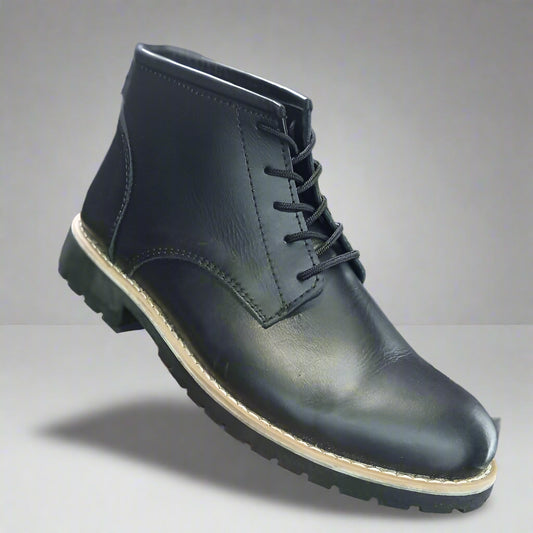 Black leather boot held in a hand with a blurred shoe store background