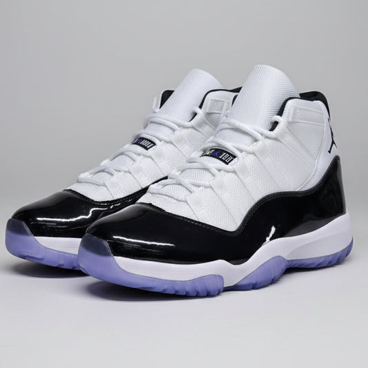 Pair of black and white sneakers with purple accents on a reflective surface.