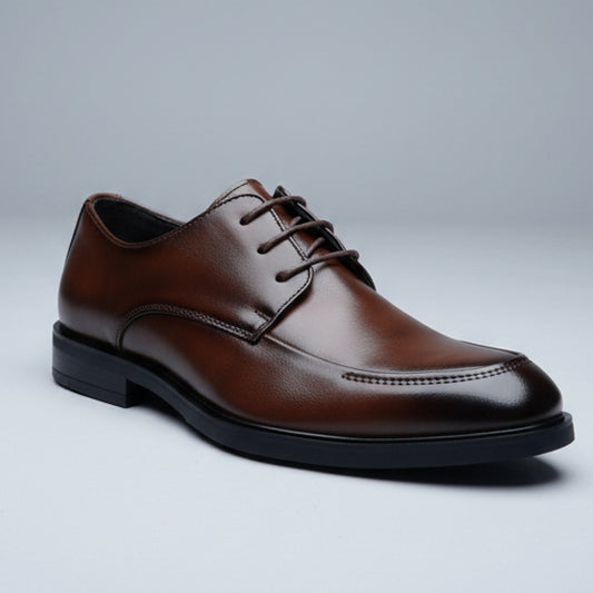 Brown leather shoe held in a hand with a shoe rack in the background